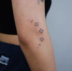 a woman with a tattoo on her arm has a small flower design on it's left arm