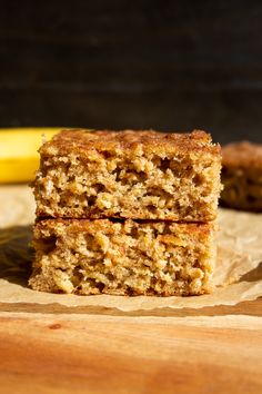 two pieces of cake sitting on top of a wooden cutting board next to a banana