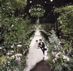 a bride and groom are sitting on the stairs in an indoor garden setting with greenery