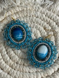 Hand made blue , pearl,  rhinestone and gold beaded dangle earrings with  blue (dyed)  agate stone center. Sewn using nylon black thread. Faux leather backing. Earring hook is hypoallergenic steel. Note: small burn mark from using a flame to clean up extra thread. These were hand crafted by me. All stones and seed beads are not uniform, which gives the overall product a more authentic and "natural" touch. <3 Bead Embroidered Bracelet, Dyed Agate, Blue Beaded Earrings, Embroidered Bracelet, Burn Mark, Earring Hook, Handmade Earrings Beaded, Le Crochet, Black Thread