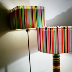 two lamps with different colored stripes on them sitting next to each other in front of a white wall