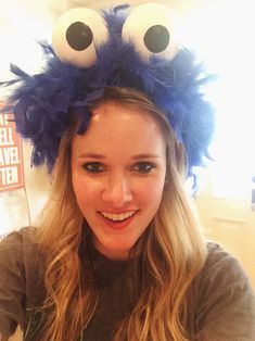 a woman with long blonde hair wearing a blue monster headband and smiling at the camera