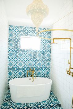 a bathroom with blue and white tiles on the walls, an oval bathtub in the middle