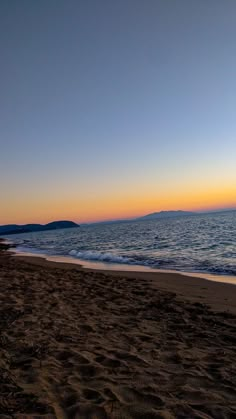 the sun is setting at the beach with waves coming in