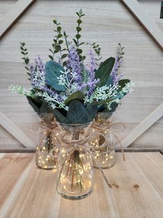 a glass vase filled with purple flowers and greenery