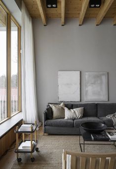 a living room with gray couches and white curtains on the window sill,