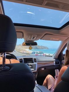 two people sitting in the back seat of a car looking out at the ocean and mountains