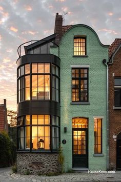 a green house with lots of windows on the front and side of it at dusk