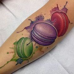 an apple, macaroni and cheese tattoo on the left arm with watercolor splashes