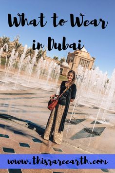 a woman standing in front of a fountain with the words what to wear in dubai