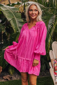 - Live your best beach life with this flowy dress! - Lightweight material with a built-in partial lining - A ruffled v-cut neckline with a tie detail - Gathered ruffles at the yoke - Long, loose sleeves with smocked cuffs - A relaxed silhouette that ends in a mini dress length hemline Hot Pink Tiered Dress, Hot Pink Mini Dress Flowy, Pink Flowy V-neck Mini Dress, Pink Flowy V-neck Beach Dress, Pink V-neck Beach Kaftan, Fun List, Loose Sleeves, V Cut, V Cuts