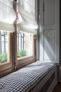 a window with some blinds on it and a bench in front of the window sill