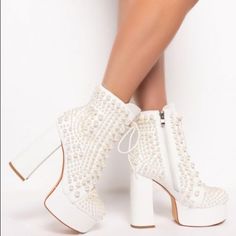 Azalea Wang Chunky Bootie In White. This Mid-Calf Height Lace Up Boot Features A Faux Leather Upper, A Platform Sole, And A Stacked Heel. Complete With Pearl Bead Embellishments And A Tonal Inner Ankle Zipper. Pair With Denim Cut Offs And Pearl Earrings For A Flirty And Feminine Look. All Man-Made Materials Lace Up Fit And Side Zipper 5.25” Heel Height, 2.5” Platform, 5.5” Shaft Height Rounded Toe Chunky Heel Chunky Mary Jane White Faux Leather Platform Boots For Party, White Synthetic Heeled Boots For Party, White Faux Leather Heeled Boots For Party, White Platform Heeled Boots For Party, Elegant White Party Platform Boots, Elegant White Platform Boots For Party, White High Heel Boots For Party, White Heeled Boots For Spring Party, White Closed-toe Party Boots