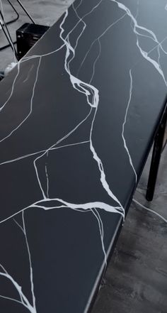 a black table with white lines painted on it's surface and two chairs in the background