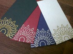 four different colored cards with gold and silver embellishments on top of each card