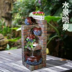 a water fountain made out of bricks with pots and flowers on it's sides