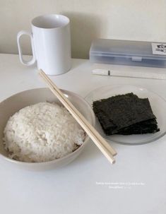 rice and chopsticks in a bowl on a table with a coffee cup next to it