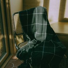 a chair with a blanket on it next to a window