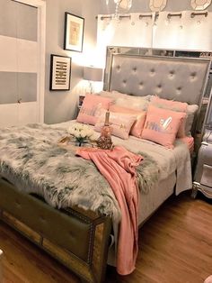 a bed with pink pillows and blankets on top of it in a room that has wooden floors