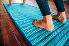 a woman standing on top of a blue mat with her feet propped up in the air