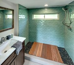 a bathroom with green tile and wood flooring, along with a wooden shower head