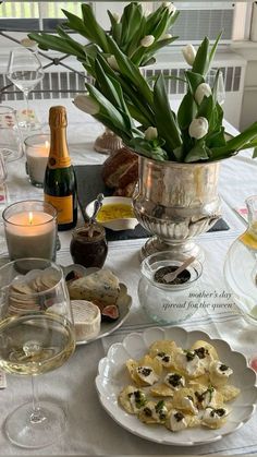 a table topped with plates and glasses filled with food next to bottles of wine on top of a white table cloth