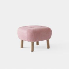 a pink foot stool with wooden legs