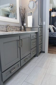 a large bathroom with gray cabinets and marble counter tops, along with a white rug on the floor