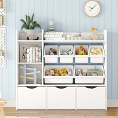 a white shelf filled with lots of toys and storage bins next to a clock