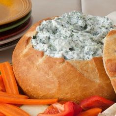 a bread bowl filled with blue cheese dip surrounded by carrots and celery