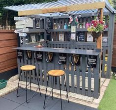 an outdoor bar made out of pallets with stools and plants on the side