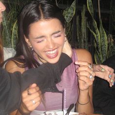 a woman sitting at a table with a cake and two other people standing around her