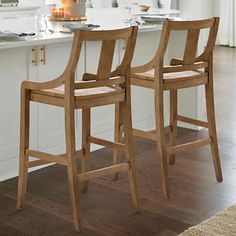 two wooden bar stools sitting on top of a kitchen counter