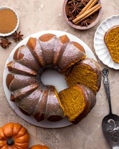 a bundt cake on a plate next to other desserts and spices, with one slice cut out