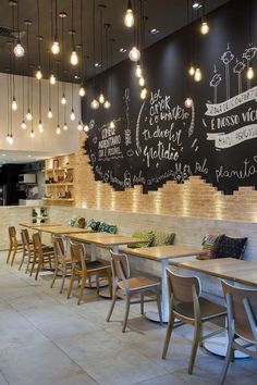 the interior of a restaurant with tables and chairs in front of a chalkboard wall