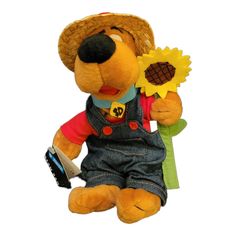 a teddy bear wearing overalls holding a sunflower