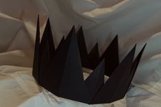 a black crown sitting on top of a white sheet