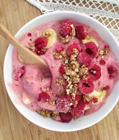 a bowl filled with ice cream and raspberries on top of a wooden table