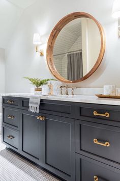 a bathroom with a large round mirror above the sink and two drawers on the side