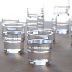 several shot glasses sitting on top of a table next to each other with water in them