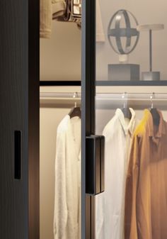 an open closet door with clothes hanging on hangers and a lamp in the background