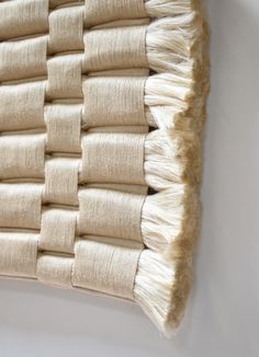 a close up of a woven wall hanging on a white wall with no one in it