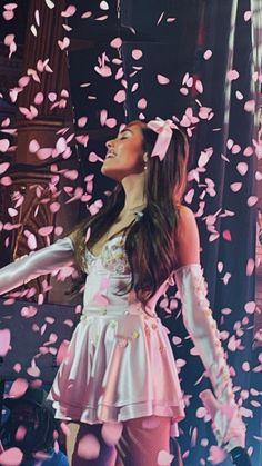 a woman standing in front of a stage with confetti falling from the ceiling