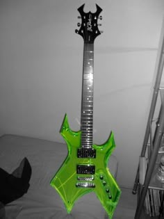 a green guitar sitting on top of a bed