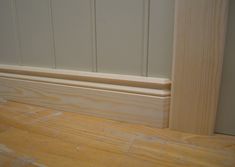 the corner of a room with wood flooring and white paint on it's walls