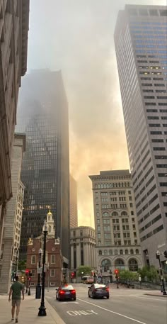 cars driving down a city street with tall buildings in the background