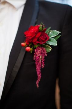 a man wearing a black suit and red boutonniere with flowers on it