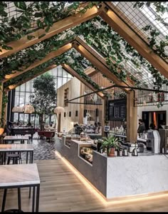 the inside of a restaurant with plants growing on the ceiling and tables in front of it