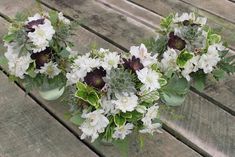 two vases filled with white flowers on top of a wooden table next to each other