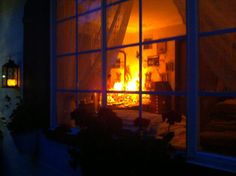 the fire is burning in the room through the window